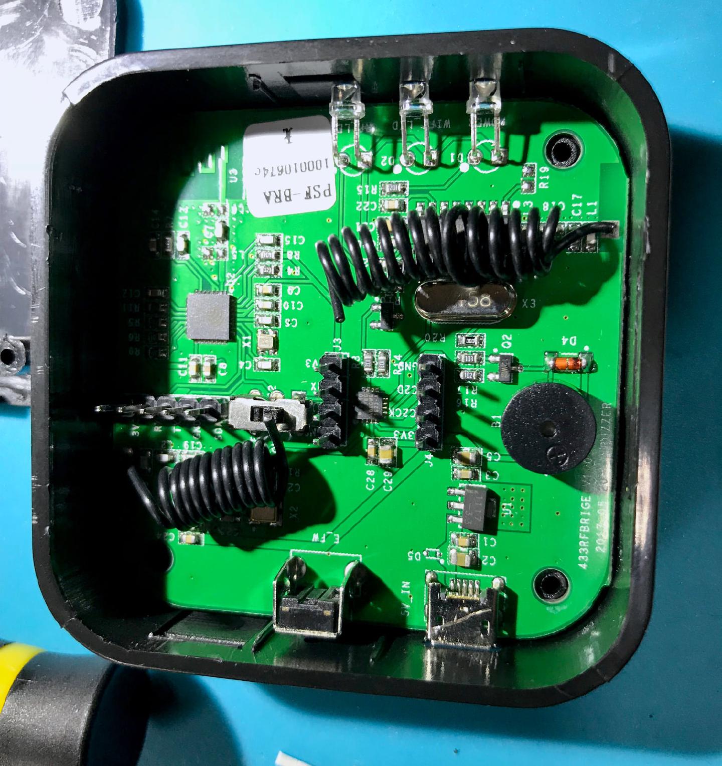 The Sonoff RF Bridge opened up, showing its two hand-wound 433 MHz coil antennas, the ESP8266 module and the serial header used for flashing