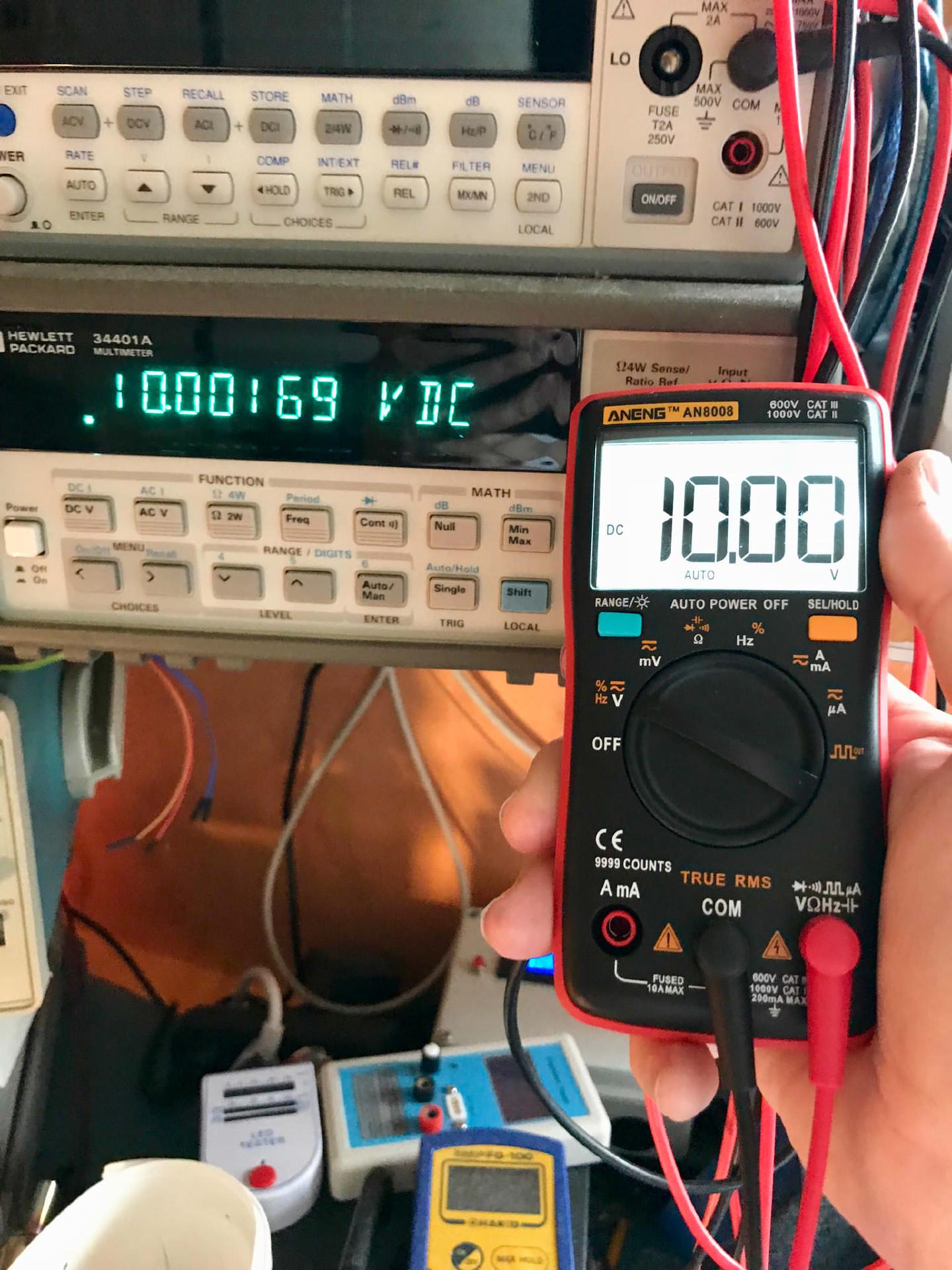 The modified AN8008 reading 10.00 V, held in front of an HP 34401A showing 10.00169 V DC