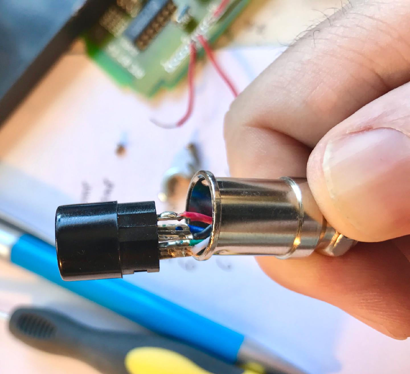 The iron’s aviation connector opened up, showing the coloured wires soldered to the pins so the temperature-sensor pin can be moved