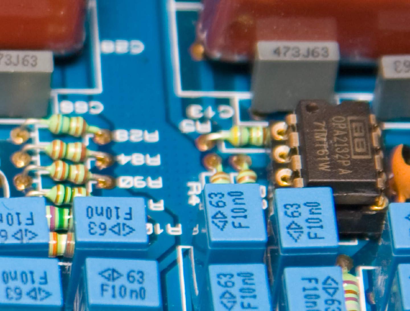 A Burr-Brown OPA2132PA op-amp seated in a turned-pin socket, surrounded by blue 10 nF film capacitors and replacement resistors