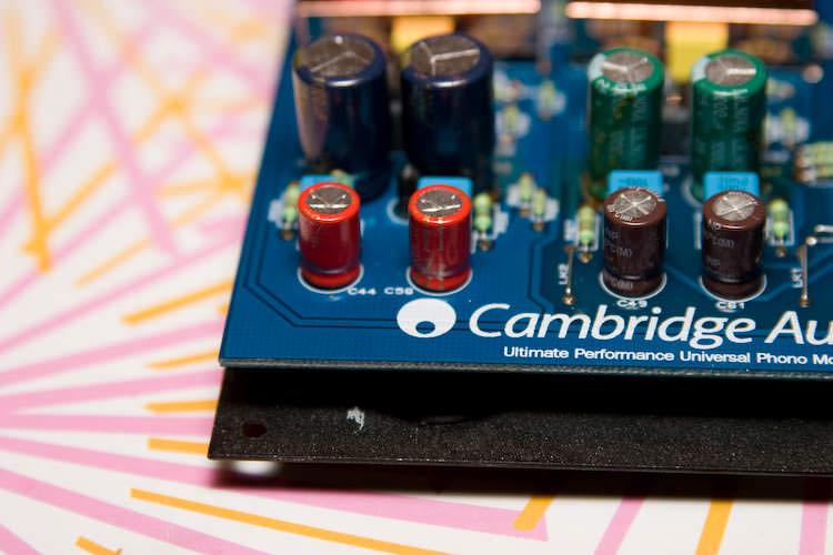 Corner of the board by the Cambridge Audio logo, red capacitors at C44 and C58 next to the original green and brown ones