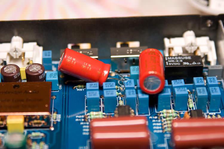 Red CE W capacitors laid over on their sides to clear the case lid, beside the Massuse relay