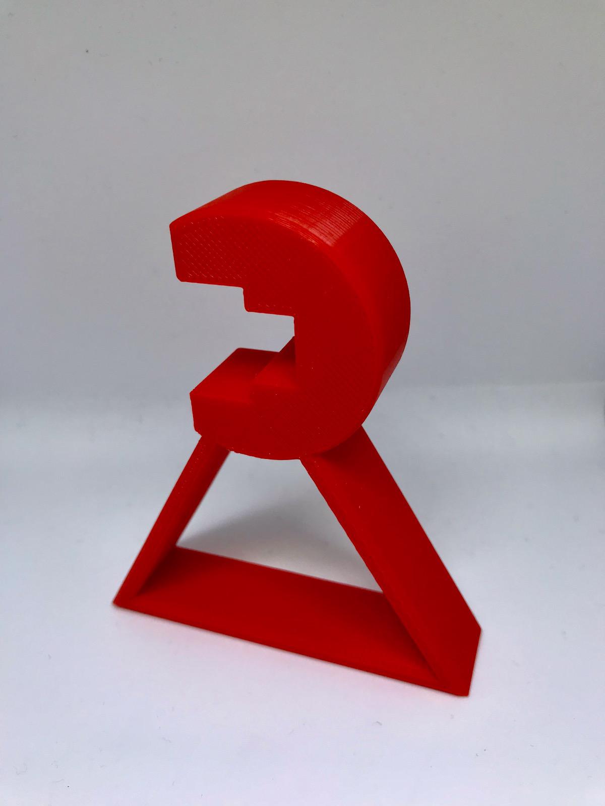 One of the red printed calibration stands, a rounded head on a triangular foot, with a notch that sits over the linear rail