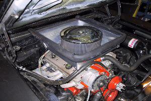 Under the bonnet: the engine with a round air filter on top and orange-painted rocker covers and pulleys