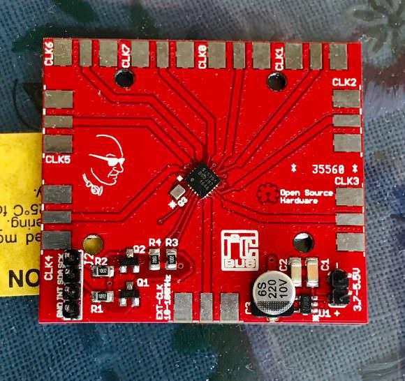 The red SI5351C breakout board, its eight CLK outputs fanning out to castellated edge pads, with the jackenface logo silkscreened on