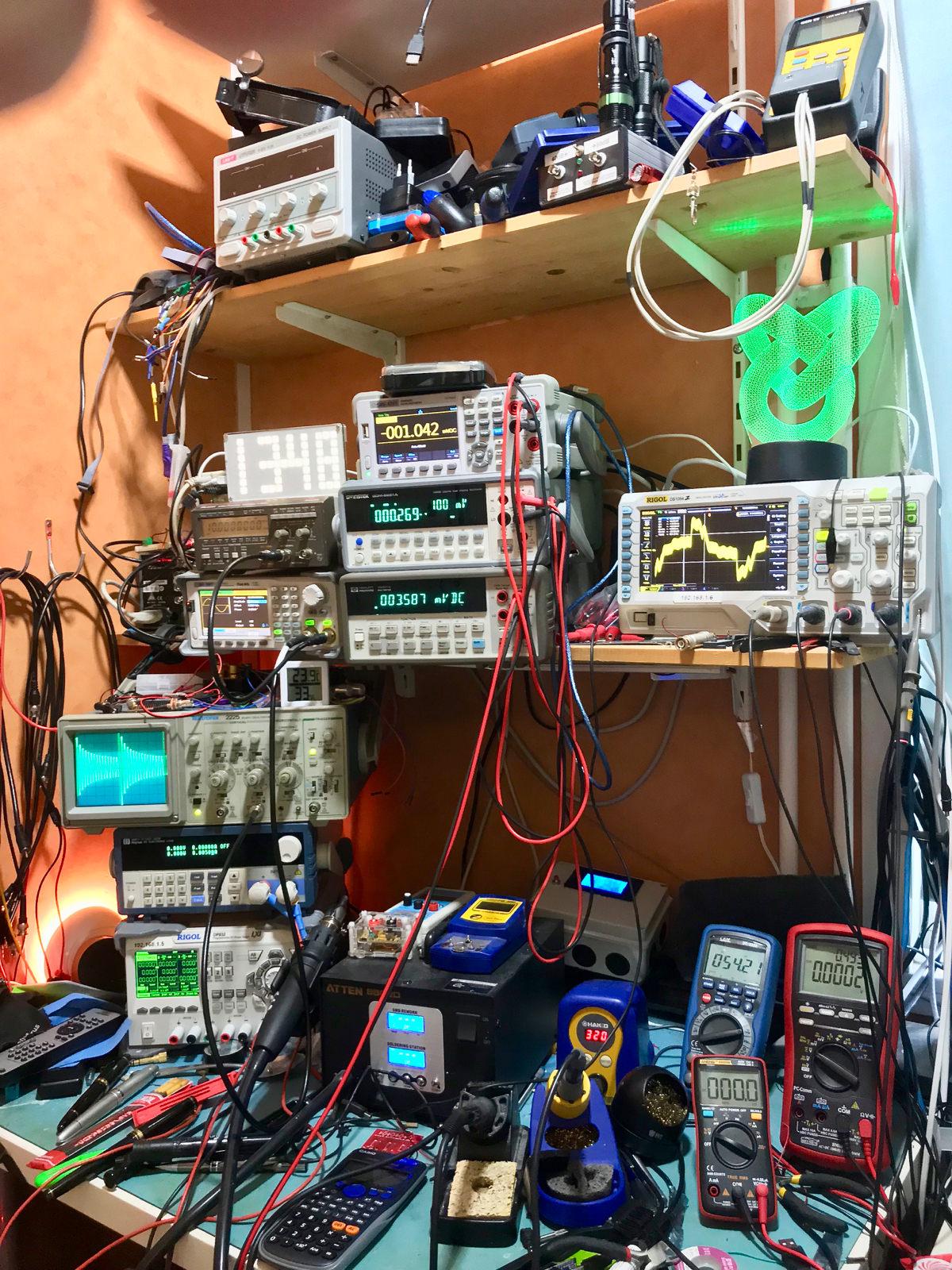 The bedroom lab: shelves packed with bench multimeters, oscilloscopes, power supplies and a soldering station, cabling running everywhere