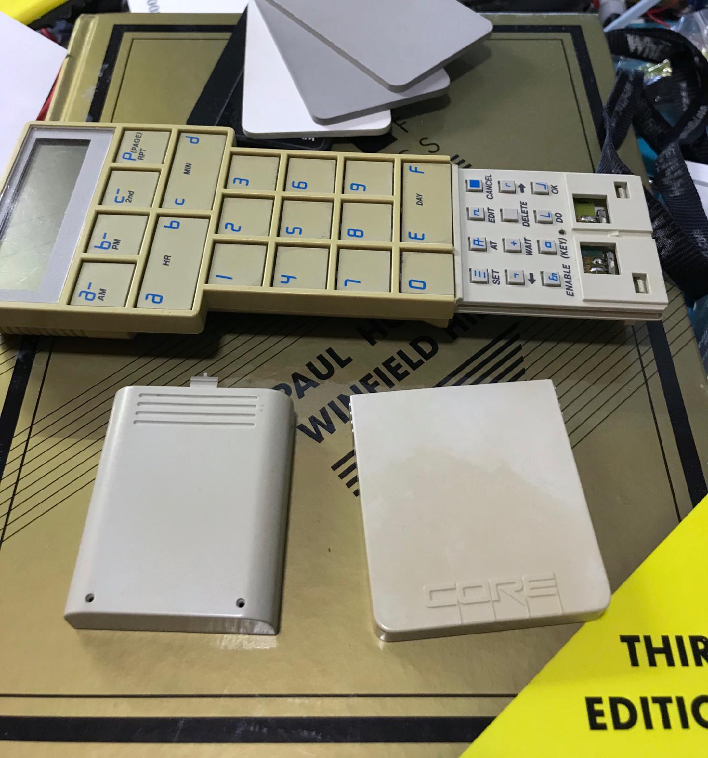 After eight hours: the treated battery cover looks like new white plastic while the front cover beside it is still noticeably yellow, both next to the calculator they came from