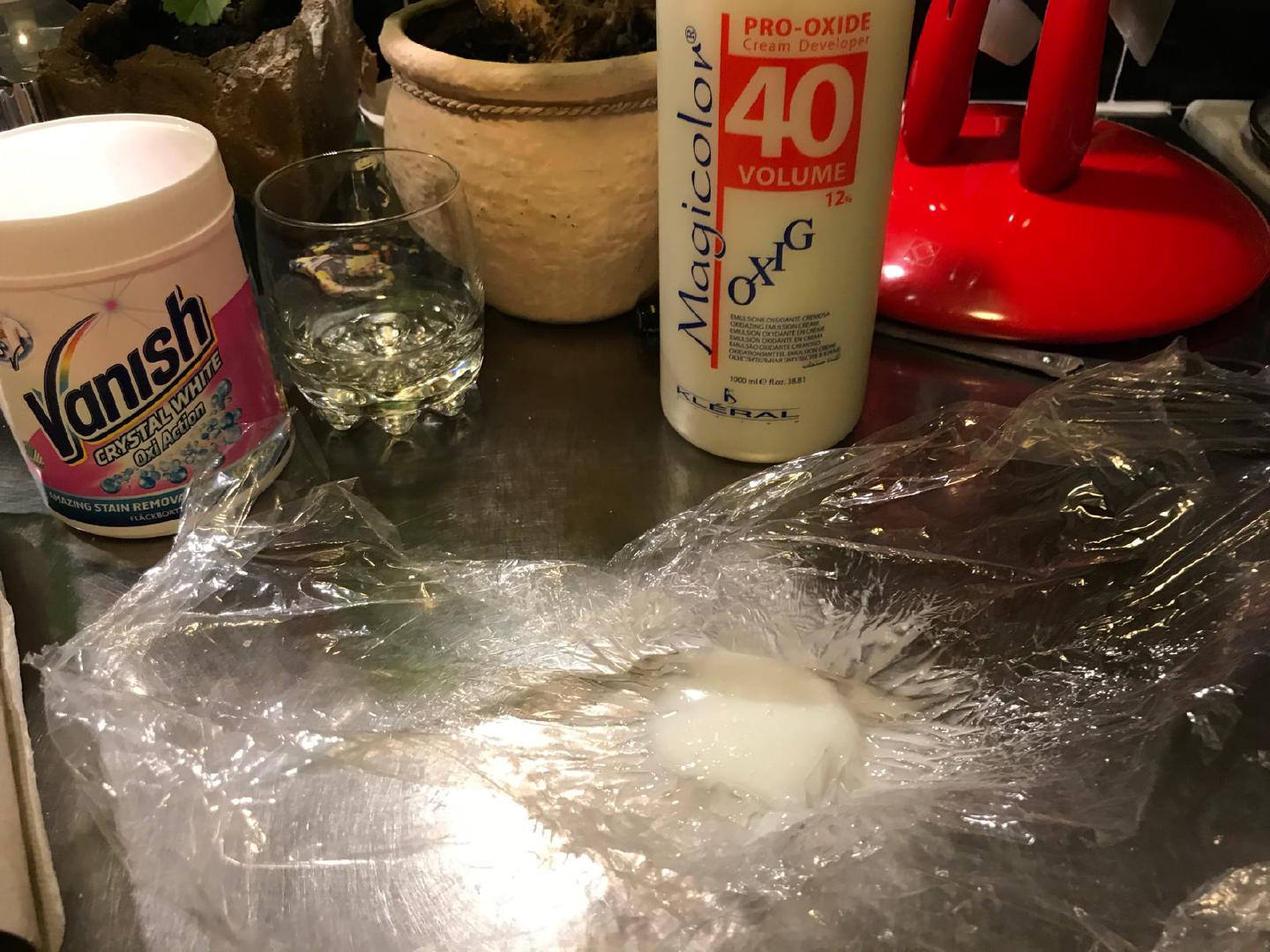 A blob of hydrogen peroxide cream on cling film, next to the tub of Vanish Oxi Action and the bottle of Magicolor 40 volume 12 percent developer it was mixed from