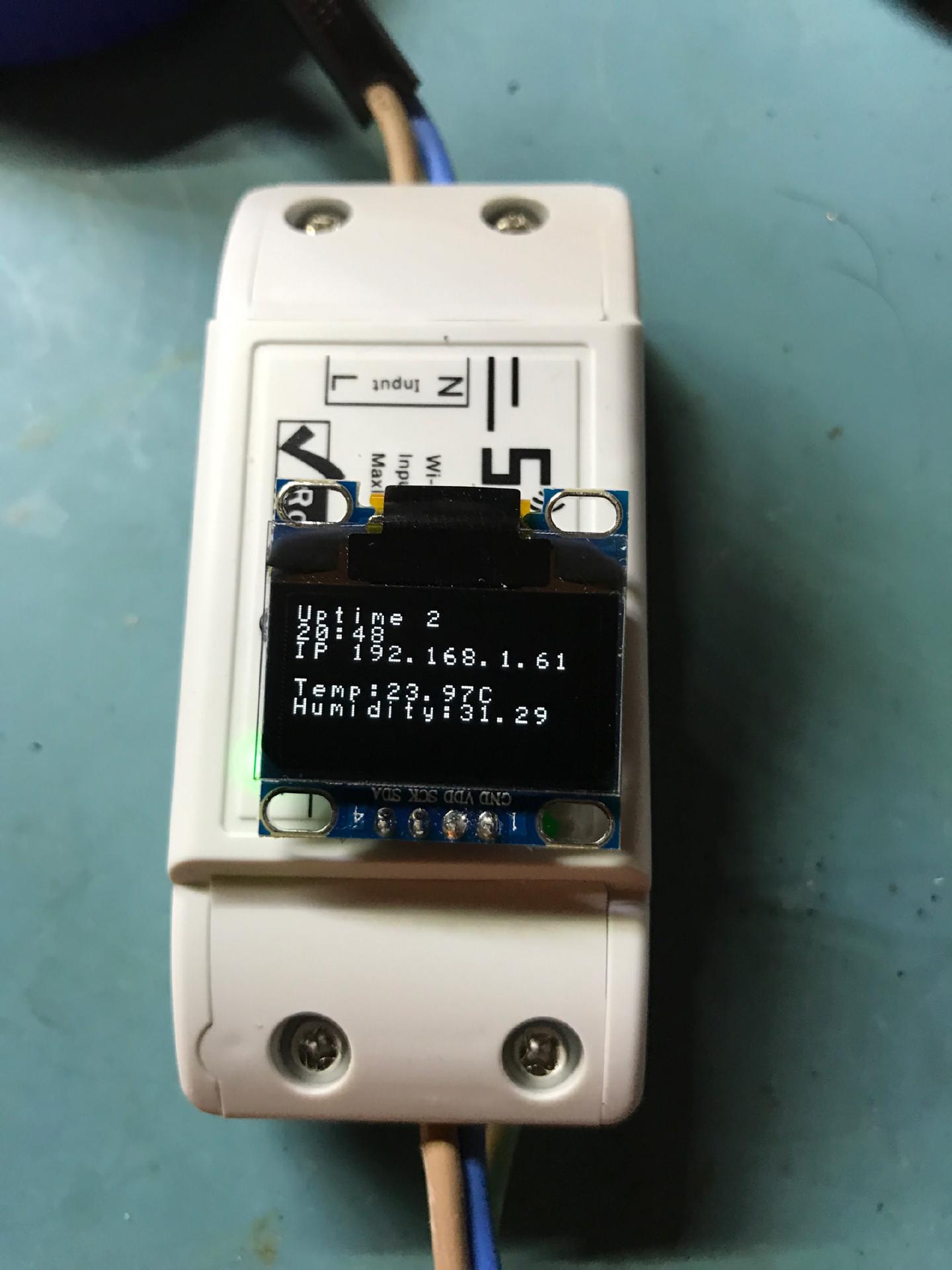 A tiny OLED module fitted to the front of a Sonoff, displaying uptime, the IP address 192.168.1.61, 23.97 C and 31.29 percent humidity